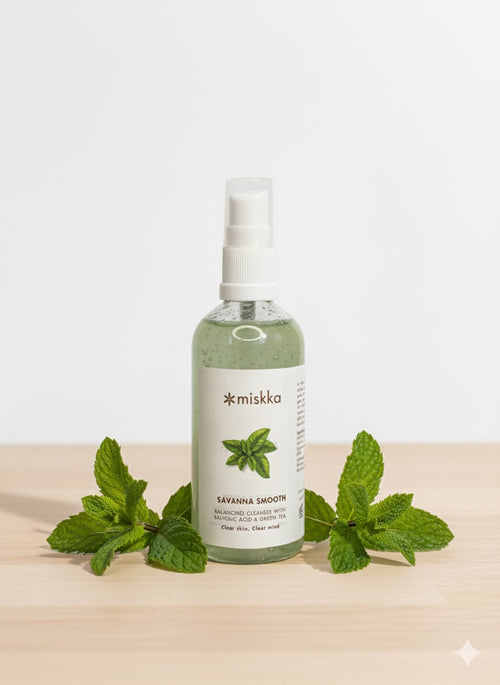 Savanna Smooth Green Tea Cleanser in a spray bottle with fresh mint leaves on a wooden surface.